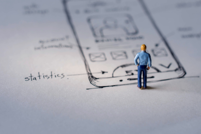 A person figure standing in front of a sketch showing user interface design